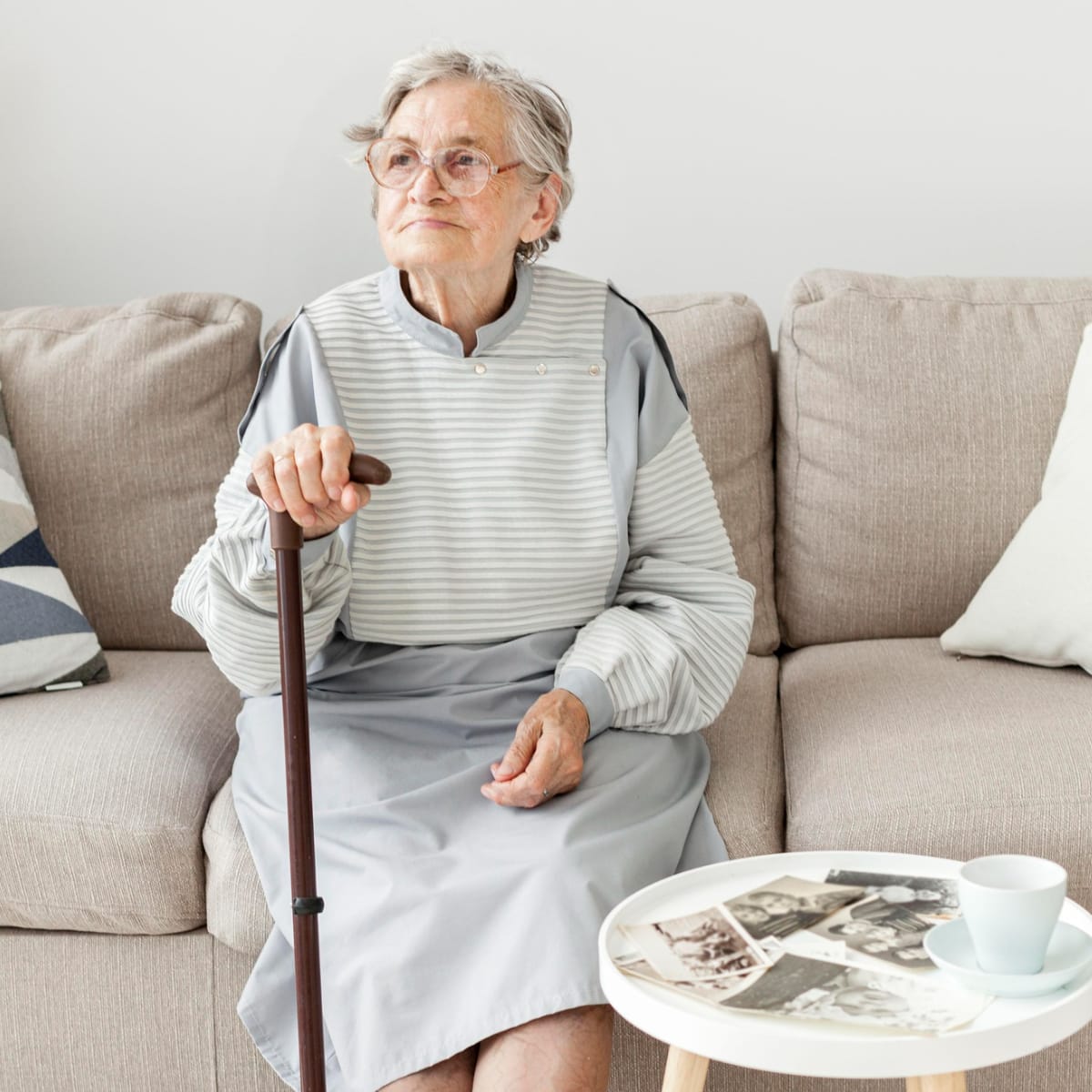 Old lady sitting on the couch holding her cane